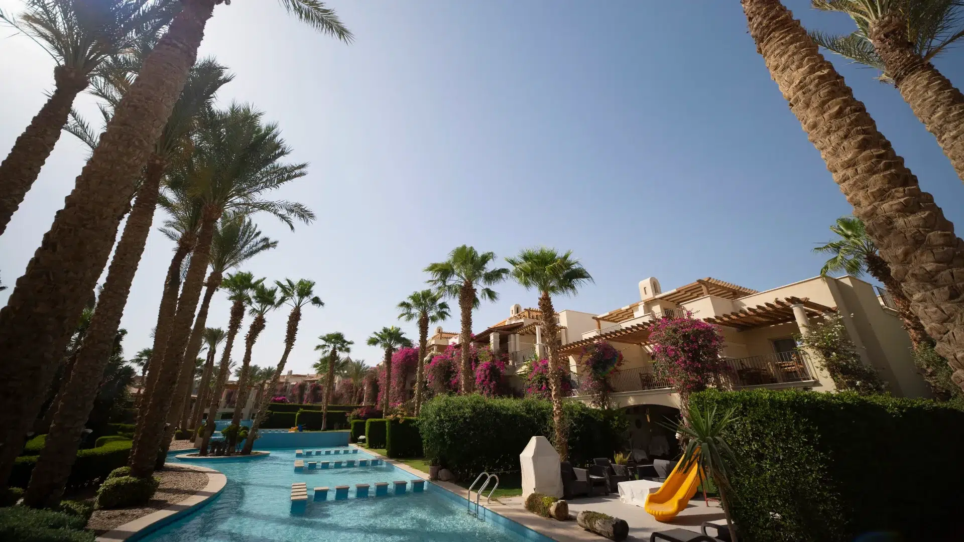 Ground-level view of a turquoise swimming pool, palms and homes at Veranda in Sahl Hasheesh