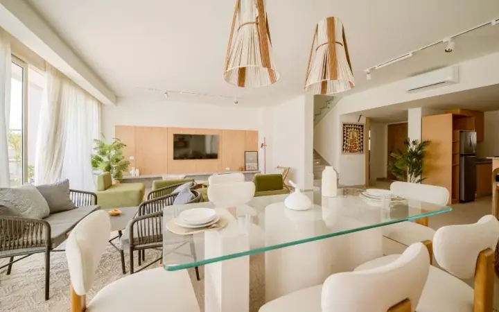 Dining table and surrounding chairs beside a living area in an iL Bayou Laguna furnished interior